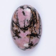 a pink and black marble ball sitting on top of a white surface