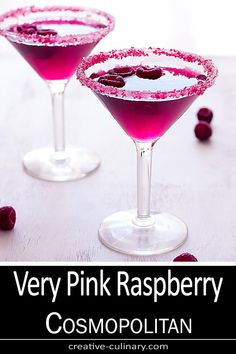 very pink raspberry cosmopolian cocktail in martini glasses with berries around the rim