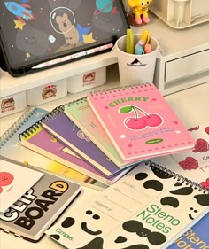 there are many notebooks on the desk with mickey mouse stickers next to it