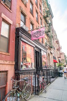 bicycles are parked on the sidewalk in front of an old - fashioned building with a pink sign