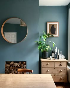 a dining room with blue walls and wooden furniture in front of a mirror on the wall