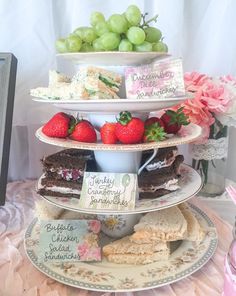 three tiered cake stand with strawberries and cakes on it, along with other desserts