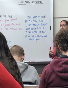 a group of people sitting in front of a whiteboard