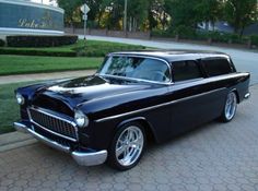 an old black car is parked on the side of the road