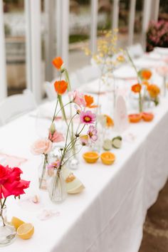 a long table with flowers in vases and wine glasses on the tables are set for an event