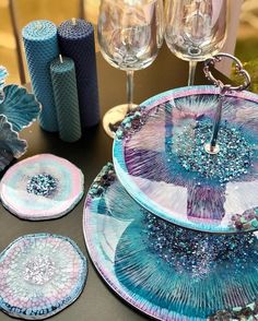 a table topped with blue and pink plates next to wine glasses, candles and napkins