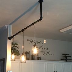 some lights are hanging from the ceiling in a room with white cupboards and cabinets