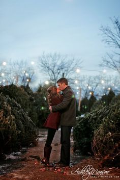 a man and woman standing next to each other in front of christmas trees