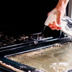 a person is using a spray bottle to wipe out something on top of a baking pan