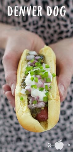 a person holding a hot dog with onions and relish