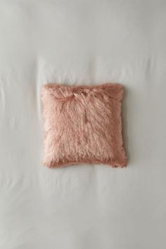 a pink pillow on top of a white bed