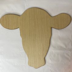 a wooden cutout of a cow's head on a white sheeted background