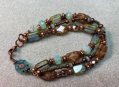 Stunning, 3 strand beaded bracelet, handcrafted with beautiful 12x8 Czech rectangle glass table-cut beads in lovely shades of Aqua Blue-opal & light Topaz. Accented with fire-polished Picasso beads, genuine copper spacers& complimenting Hawaiian hibiscus & wire wrapped Dahlia coin bead. Finished off with a length of glistening deep earth-tone seed beads.  All my bracelets are approximately 7.5 inches in complete length, wear loosely or lightly twist for a snugger fit Enjoy Free shipping througho Bohemian Double Strand Bracelet With Faceted Beads, Beaded Car Charms, Czech Beads Jewelry, Czech Glass Bead Bracelet, Leather Earring, Hawaiian Flower, Multi Strand Bracelet, Assemblage Jewelry, Necklace Sets