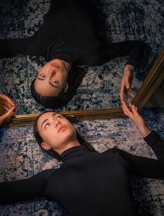 two women laying on the floor in front of a mirror looking up at their faces