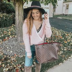 a woman in pink sweater and black hat holding a brown louis vuitton bag