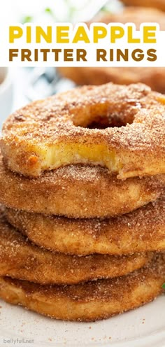 a stack of pineapple fritter rings on a white plate with cinnamon sprinkles