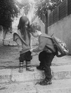 two young children standing on the steps playing with each other's shoes and backpacks