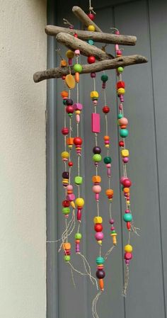 a wind chime hanging from a tree branch with colorful beads and wooden sticks attached to it