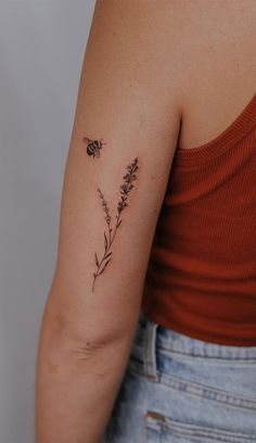 a woman with a tattoo on her arm and a bee sitting on top of it