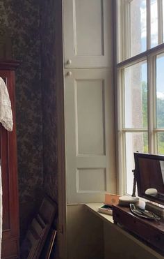 an old fashioned dresser in front of a window with a dress hanging on it's hanger