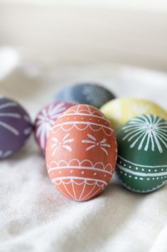 four painted easter eggs sitting on top of a bed next to each other in different colors