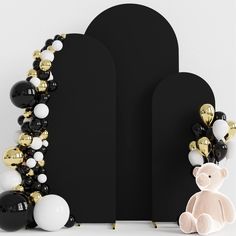 a teddy bear sitting next to some balloons and a black board with gold trimmings