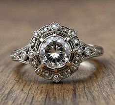 an old - fashioned engagement ring with a diamond in the center on a wooden surface