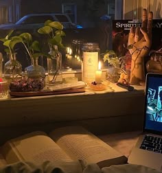 an open laptop computer sitting on top of a window sill next to a book