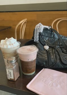 a table topped with two cups of coffee next to a purse