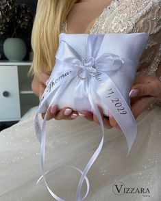 a woman holding a white wedding ring pillow