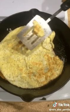 an omelet is being cooked in a skillet on the stove with a spatula