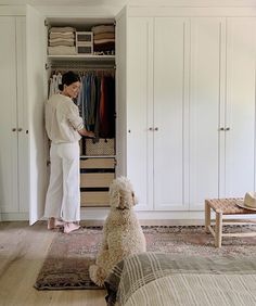 a woman standing in front of a closet with a dog