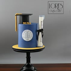 a graduation cake with a mortar and diploma cap on top, sitting on a pedestal