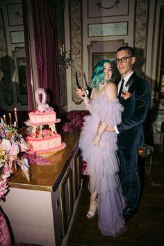 a man and woman standing in front of a cake