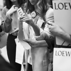 a group of women standing next to each other holding signs and looking at their cell phones