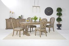 a dining room table and chairs with a clock on the wall above it, in front of a white rug