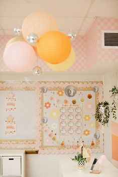 a room with pink and yellow decorations on the walls, white desks and drawers