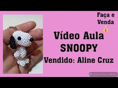 a hand holding a small beaded dog in it's right hand with the words video aura snoopy written below