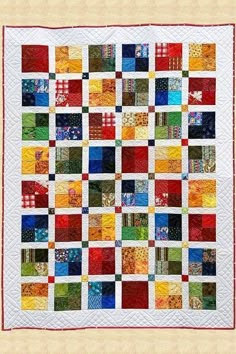 a quilt made with many different colors and patterns on the front, along with an orange border