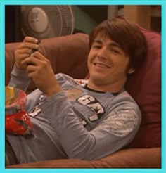 a young man laying on top of a couch holding a cell phone in his hand