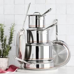 pots and pans stacked on top of each other in front of a white tiled wall