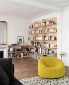 a living room filled with furniture and a book shelf next to a fire place in front of a fireplace