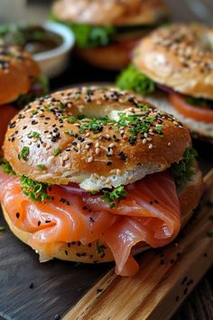 bagel sandwiches with salmon, lettuce and other toppings on a cutting board