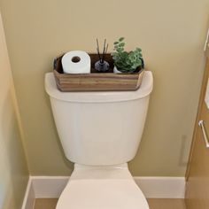 a white toilet sitting in a bathroom next to a wooden shelf filled with toilet paper