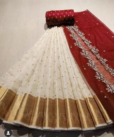 a white and red sari with gold border on the bottom, sitting on a table