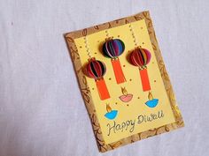 a card with two hot air balloons hanging from it's earwires on a table