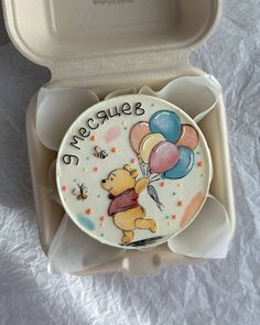 a winnie the pooh plate with balloons and stars on it in an open box