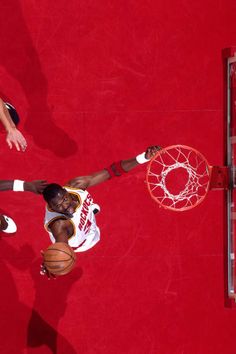 two men playing basketball on a red court