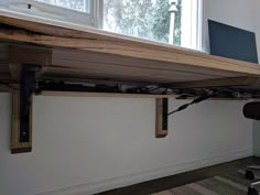 a wooden shelf with wires attached to it and a window in the backround