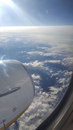 the view from an airplane window shows clouds and bright sun in the sky, as seen from above